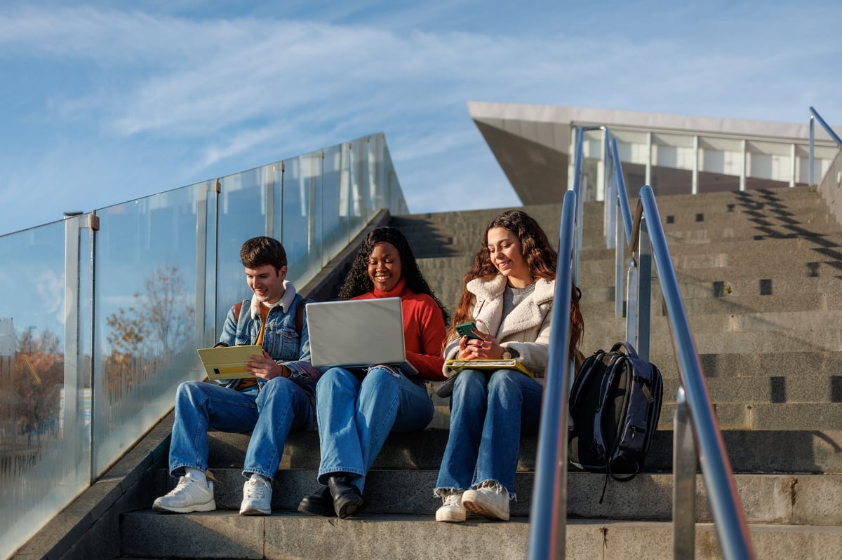 Diverse students sitting on campus steps learning together